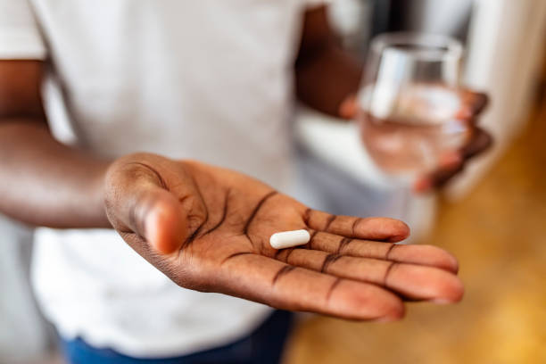 Time for my daily boost Unrecognizable African American man ready to take a pill while standing at home, copy space sleeping pill stock pictures, royalty-free photos & images