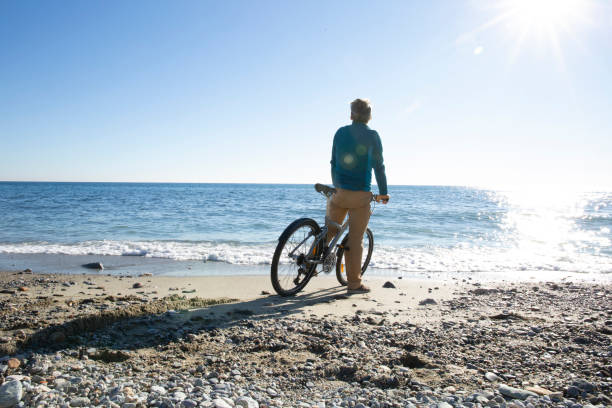 istock Man riding bicycle relaxes on beach in the morning 1286866363