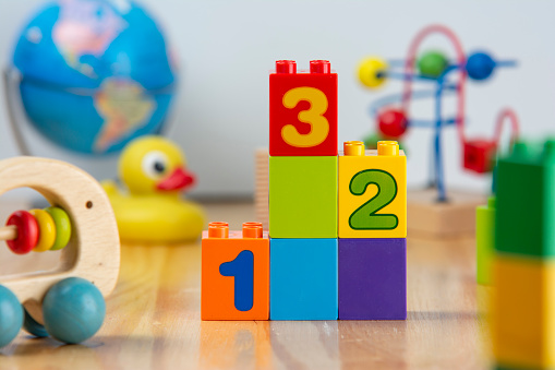 A series of numbered toy building blocks are surrounded by other colorful toys.
