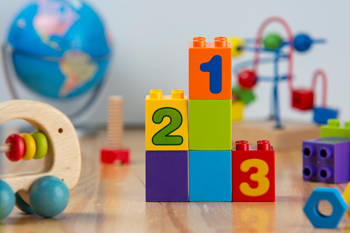 A series of toy building blocks, numbered and arranged like a podium, are surrounded by other colorful toys.