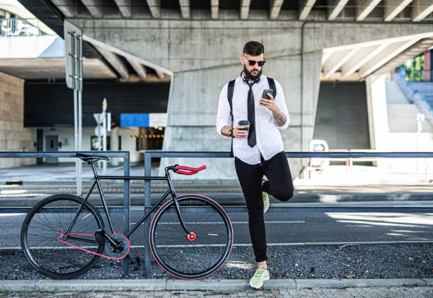 istock Young man commuter with bicycle standing outdoors in city, using smartphone. 1286872957