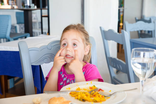 istock little girl making faces with paella dish in restaurant 1286876055
