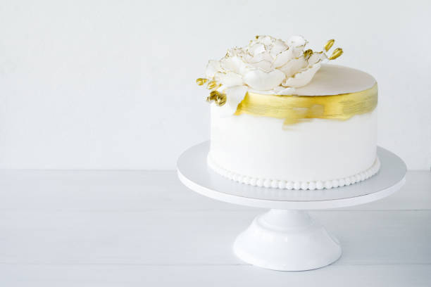 istock White wedding cake decorated with gold flowers on a white background. 1286877282