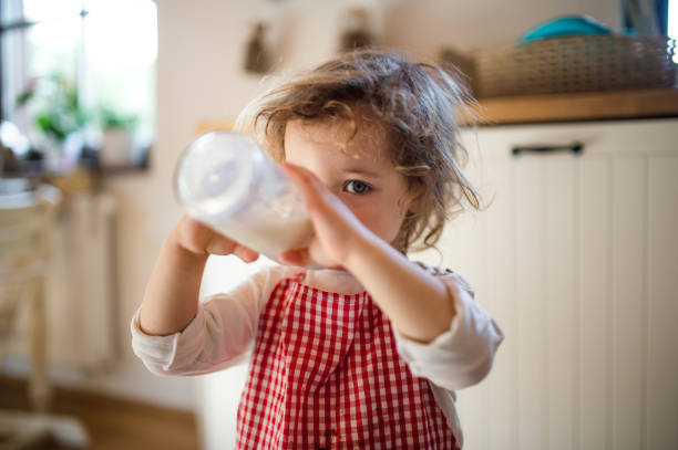 istock Small girl indoors in kitchen at home, drinking milk from bottle. 1286879747