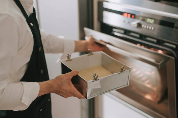 An asian chinese chef pulling dough tray from oven in kitchen baking preparing meal