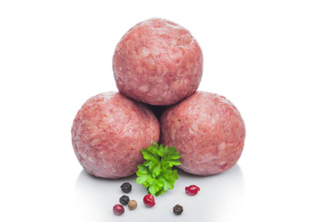 Fresh raw beef meatballs with pepper and parsley on white.