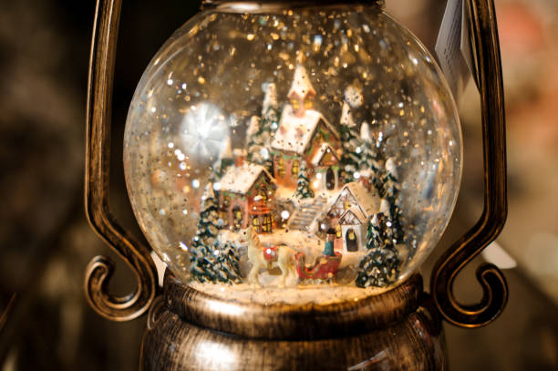 close-up view on small town with snowy houses inside transparent round Christmas ball close-up view on beautiful small town with bright snowy houses inside transparent round Christmas ball snow globe photos stock pictures, royalty-free photos & images