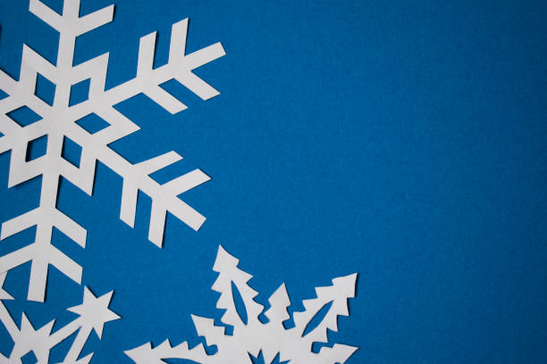 istock White paper handmade snowflakes on blue colored paper background 1286889661