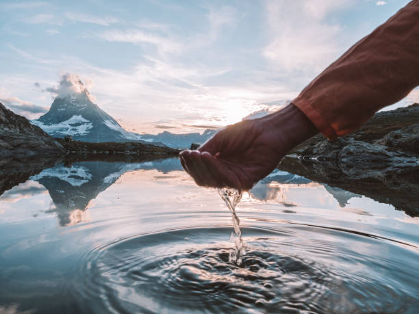 detail of hand cupping water in mountain lake below the matterhorn mountain - mountain drop europe switzerland imagens e fotografias de stock