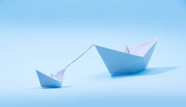 istock Paper boats - Tugboat or Remorker pulling a big boat 1286891299
