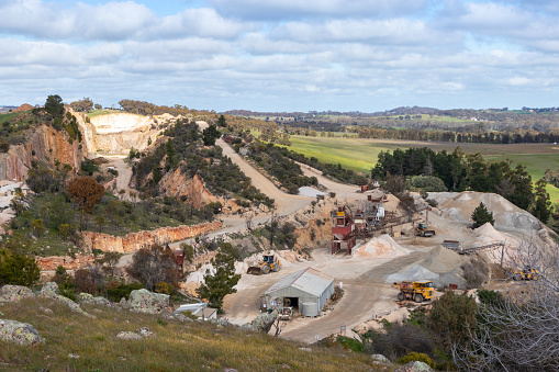 Trucks and machinery working at a stone quarry, exploitation of natural resources. Open air mining activity at Clare valley, South Australia