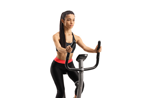 Young woman in sportswear exercising on a stationary bike isolated on white background
