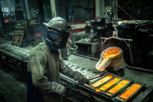 Pouring liquid gold metal into graphite casting form from inductive furnace with shielding gases in production plant closeup