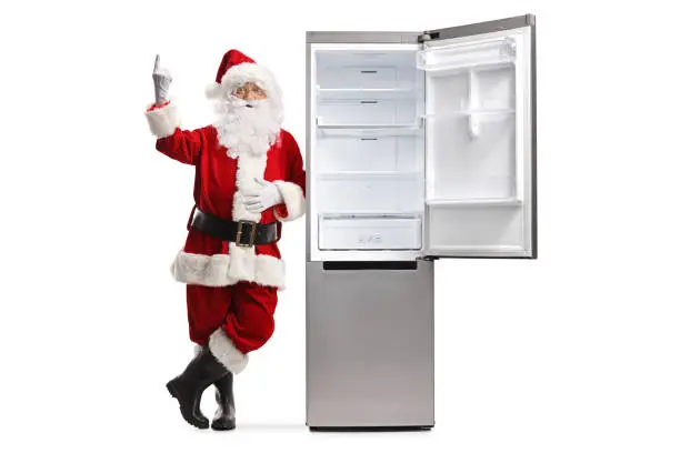 Photo of Santa claus leaning on an empty open fridge and pointing up