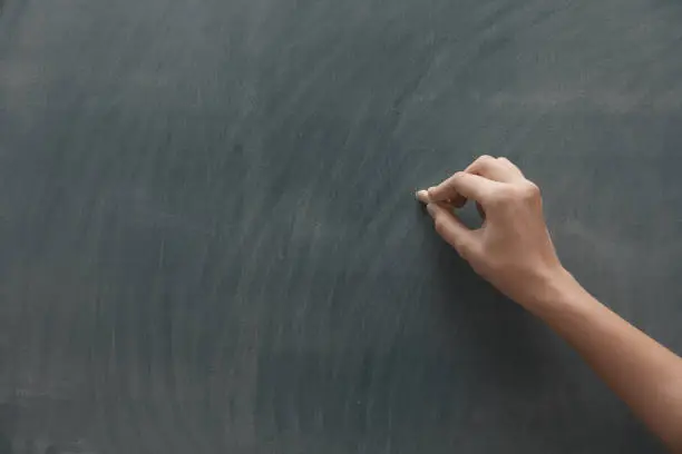 Photo of Human hand with chalk at the blackboard