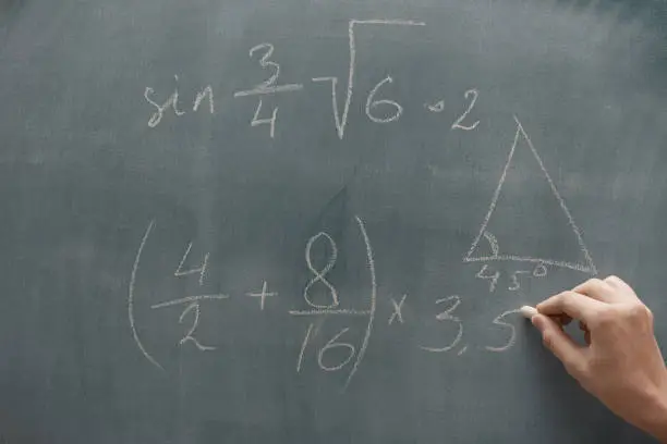 Photo of Hand of student studying mathematics and writing on a blackbroard