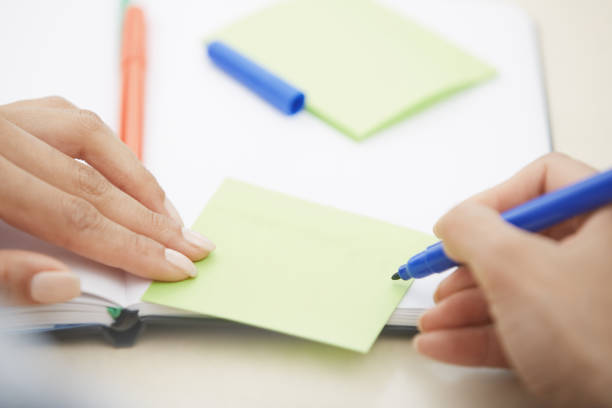 istock Hands of woman writing on adhesive note with empty space 1286903301
