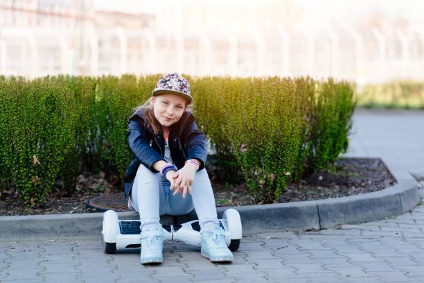 istock Smiling girl in a baseball cap sits on a hoverboard. 1286905459