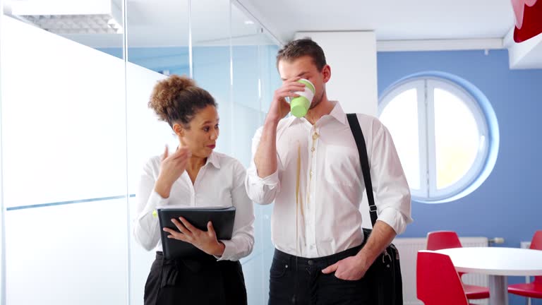 Caucasian Businessman Spills Coffee on the Shirt while Walking with African-American Businesswoman