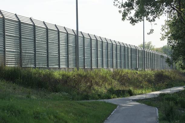 istock long  gray iron fence wall in green grass 1286910597