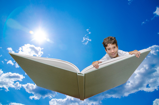 Boy flying on a book  seen from front,
This is to represent the pleasure of reading and the fact that reading is making the reader traveling to many worlds, magical or real.