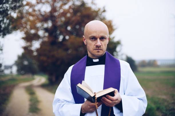 istock Catholic priest reading bible on a country road 1286919514
