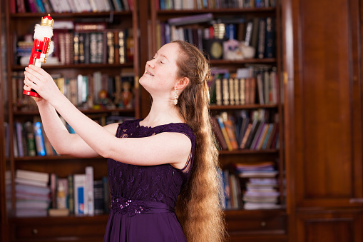 A 15 year old girl in purple dress with long dark blonde hair in profile holding a nutcracker she got as a present on that same new year's eve. The Nutcracker is generic and can be found everywhere.
