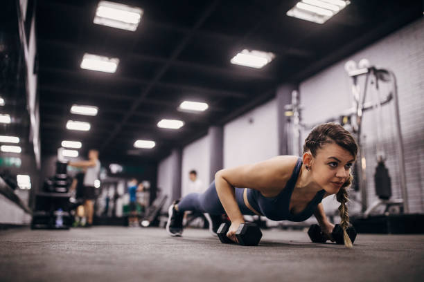 istock Fit woman doing push-ups on dumbbells in gym 1286922991