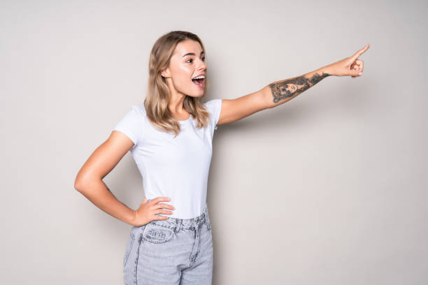 istock Excited woman point finger showing something to side empty copy space isolated over white background 1286935476
