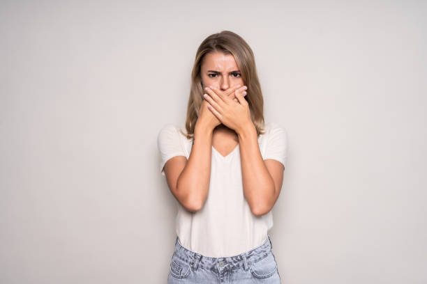 istock Young woman covers mouth with hand, isolated on white background 1286935520