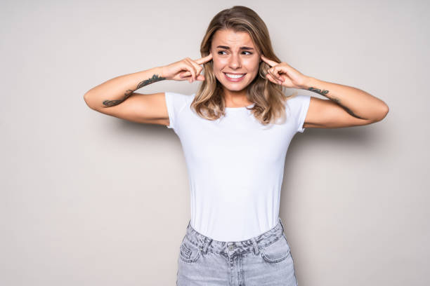 istock Sad young woman covering her ears isolated on white background 1286936021