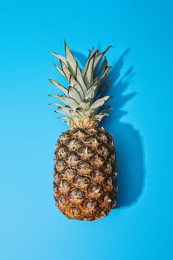 top view of whole ripe pineapple on blue colorful background