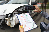 frau-fotografiert-ein-kaputtes-auto-auf-