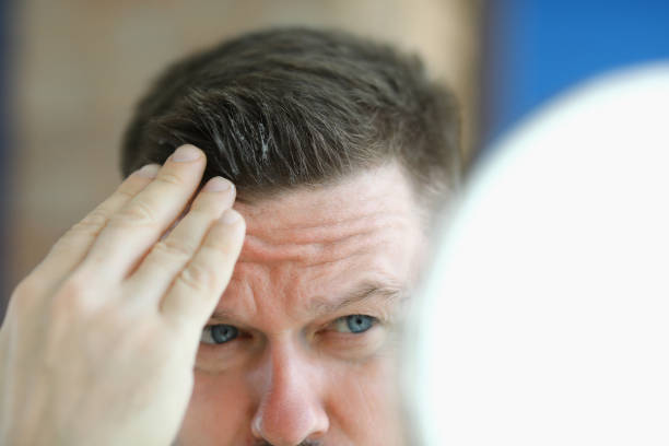 istock Man does gel hair styling in front of mirror. 1286940841