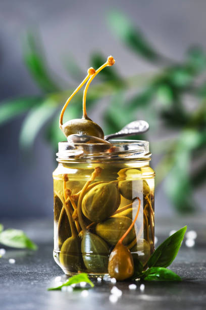 istock Marinated or pickled canned capers fruit close up in jar on gray kitchen table with copy space 1286940940