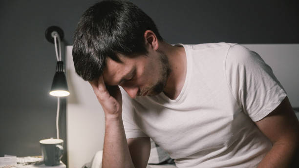 istock Sick man in bed measuring temperature feeling fever. High temperature concept. Man feels badly ill. Cold symptoms and causes. Sick man with flu. Man hold thermometer. Measure temperature 1286941361