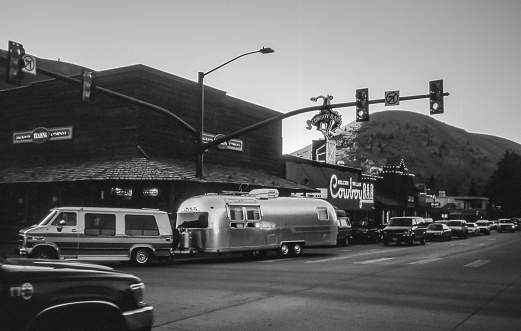 Jackson Hole, Wyoming, USA - July 21, 1995: An Airstream trailer from the 1950s - 1960s, still in perfect use, passes through the streets of Jackson Hole on its way to Yellowstone N.P. Styled black white photo.