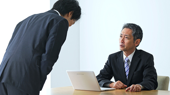 Scolding middle aged asian businessman in office.