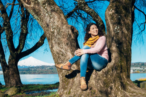Woman sitting under a tree smiling and enjoying nature. Concept of freedom and happiness Woman sitting under a tree smiling and enjoying nature Concept of freedom and happiness tremoctopus gelatus stock pictures, royalty-free photos & images