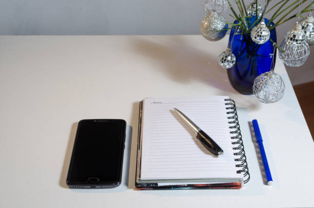 White workspace with blue and silver  christmas decoration, notebook , smartphone and pens. Christmas and new year concept. Working at home.
