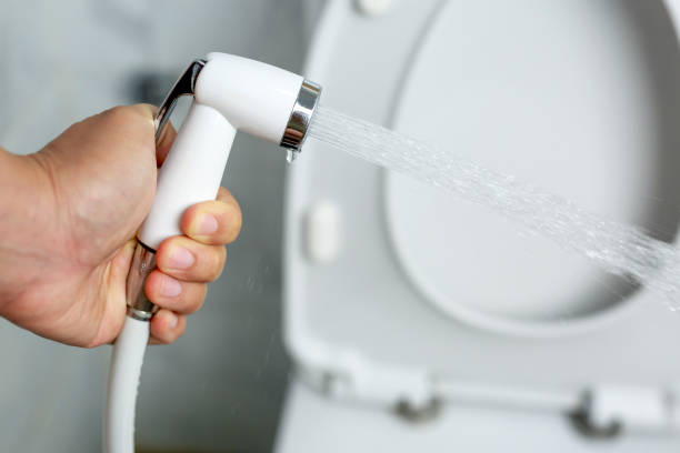 White handheld bidet sprayer in toilet bathroom stock photo