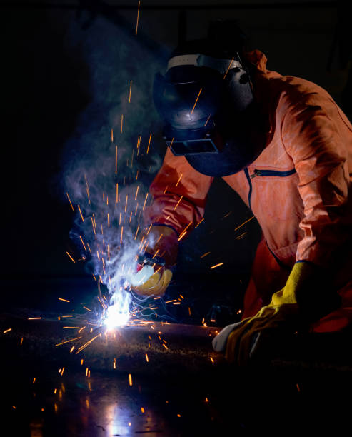 istock Metal industry workers are welding steel sheets for real estate projects received. Sparkler on dark background, close-up. Heavy work in factory. 1286961507