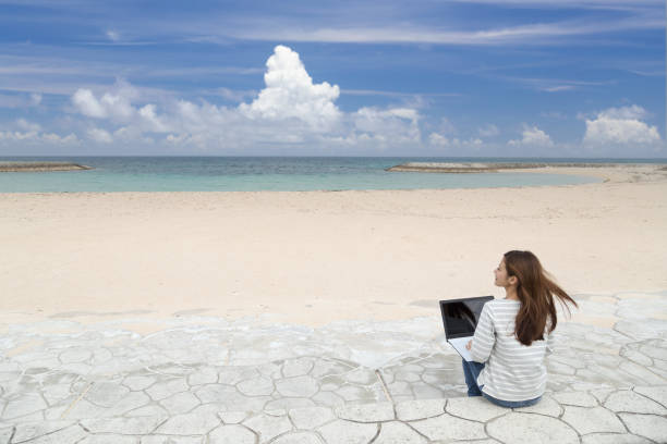 istock A woman teleworking on the beach in Okinawa 1286964218