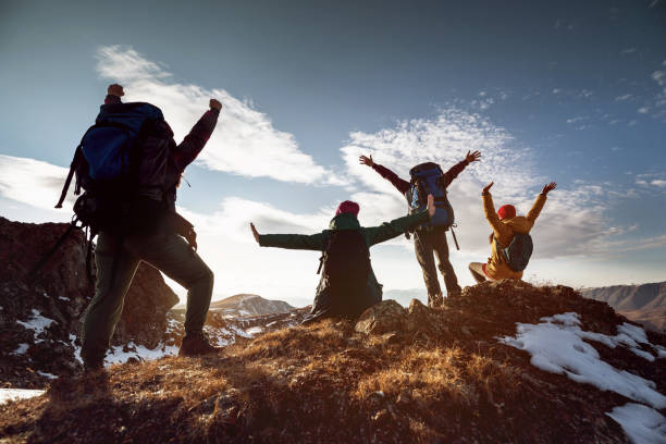 istock Hikers in winner poses stands at mountain top 1286977673