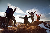 Hikers in winner poses stands at mountain top