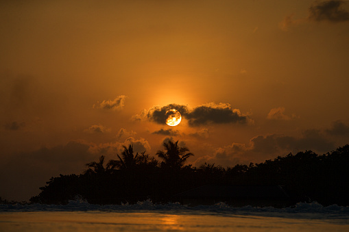 Golden, tropical sunset behind island
