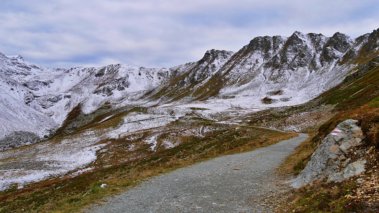 Hiking path with trail marking leading through snow-covered Madrisa mountain range in Rätikon massif near Gargellen, Montafon, Austria, a popular tourist destination and hiking area, in autumn season.