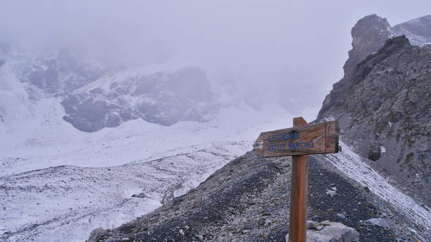 segno di legno con freccia che segna il sentiero escursionistico sul ghiacciaio "suldenferner" nel massiccio montuoso ortles innevato vicino a sulden, alto adige, italia nelle alpi con nebbia. - sulden foto e immagini stock