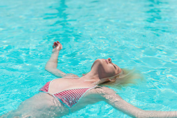 istock Young woman floating on back in swimming pool 1286983722