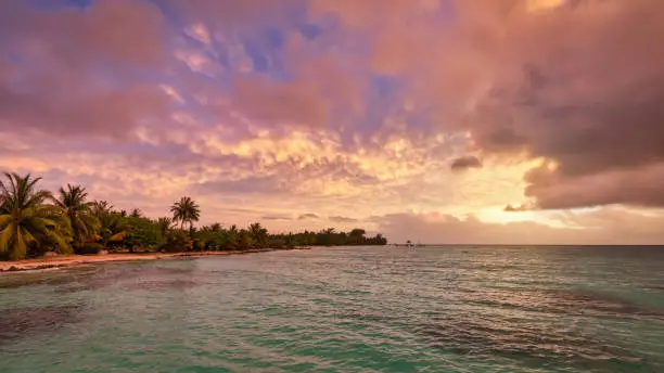 Fakarava Atoll Sunset Panorama. Colorful sunset clouds and skyscape over the natural beach and turquoise south pacific ocean lagoon seascape of the Fakarava Atoll. Fakarava Island, Havaiki-te-araro - Farea, Tuamotu Atolls, French Polynesia, Oceania